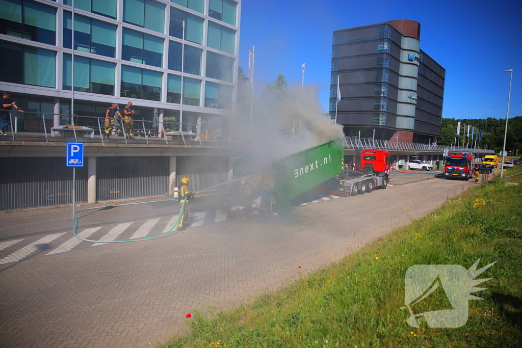 Vlammen slaan uit grote afvalcontainer