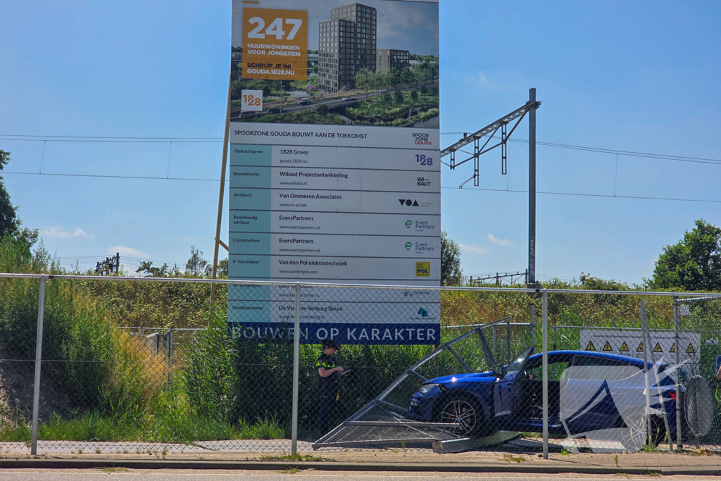 Automobilist ramt hekwerk bij bouwplaats