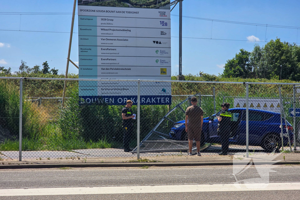 Automobilist ramt hekwerk bij bouwplaats