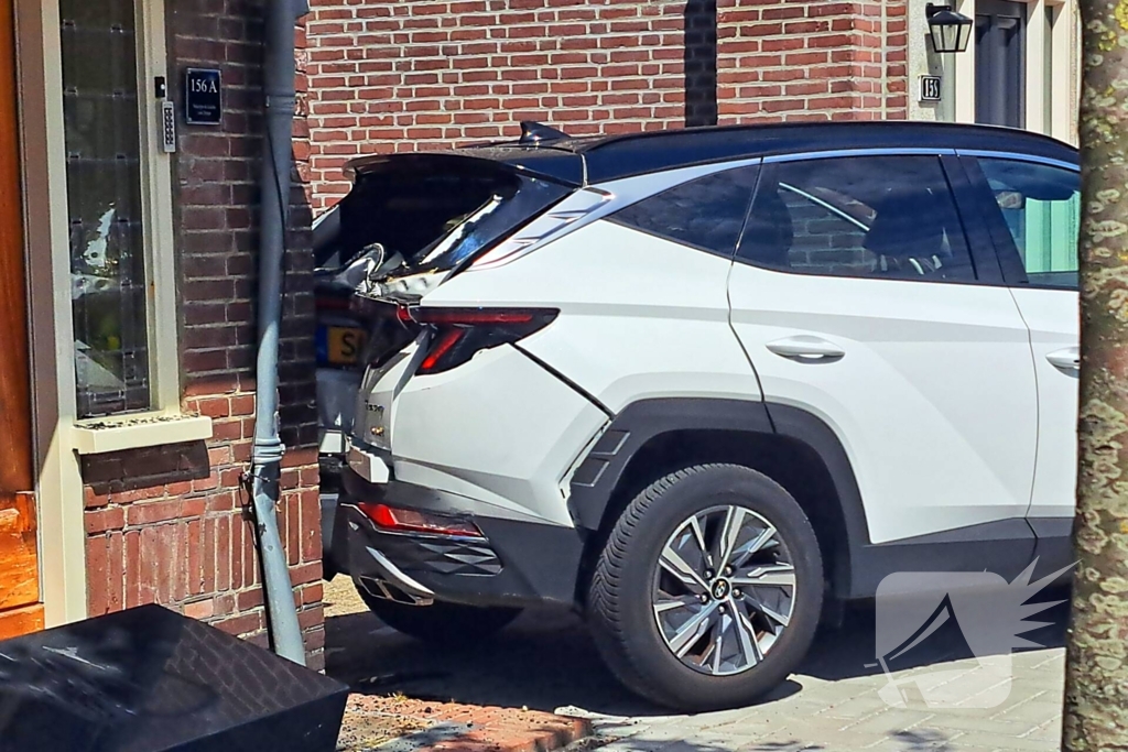 Auto rijdt achteruit tegen woning
