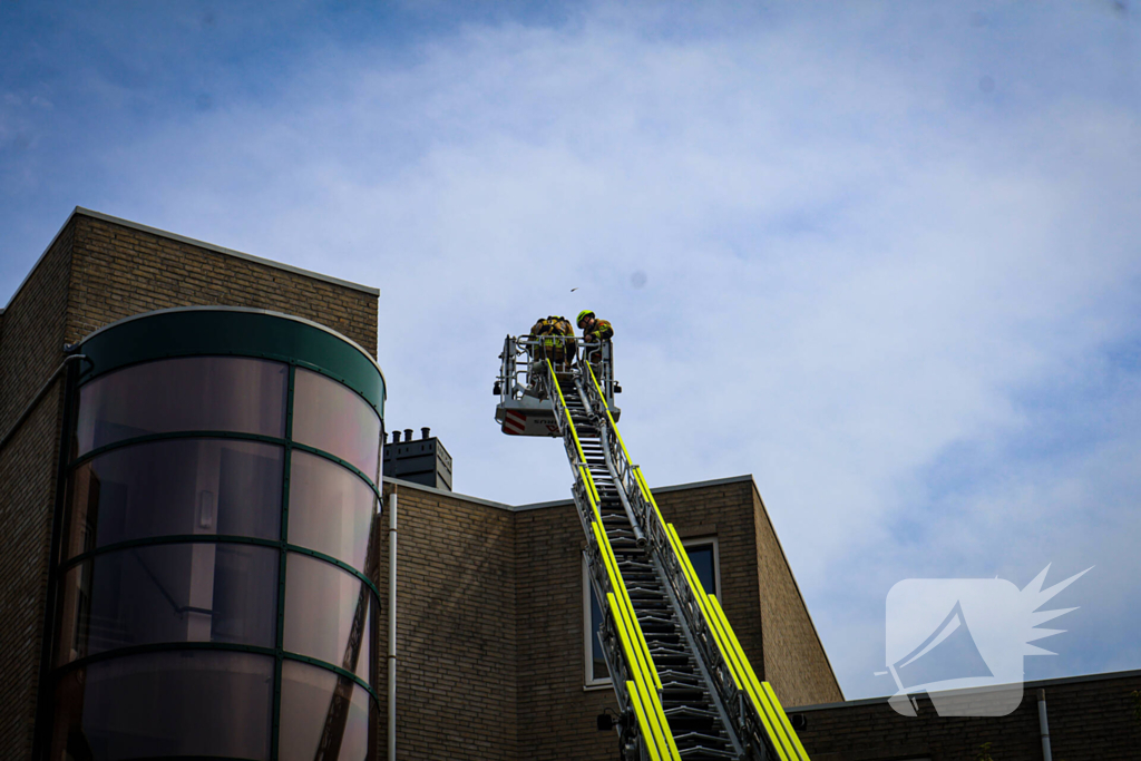 Los gewaaide parasol belandt op dak appartementencomplex