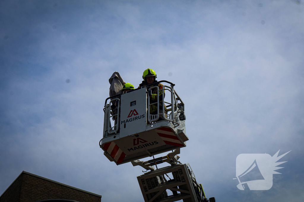 Los gewaaide parasol belandt op dak appartementencomplex