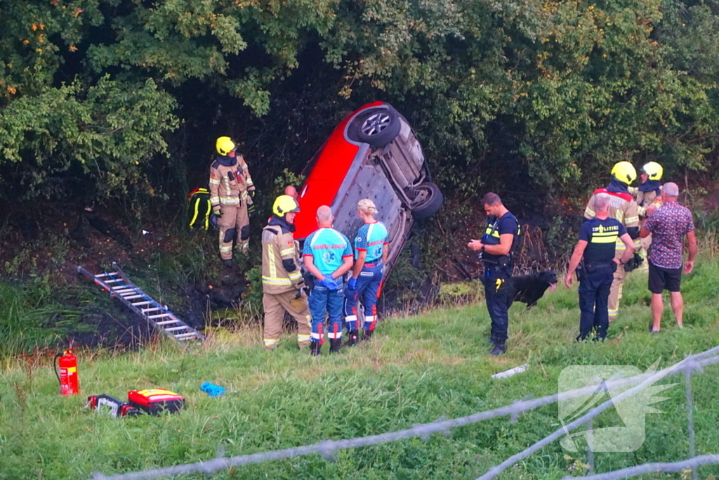 Auto rijdt van dijk af en slaat voorover