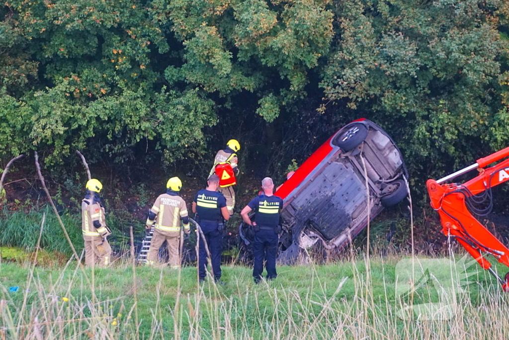 Auto rijdt van dijk af en slaat voorover