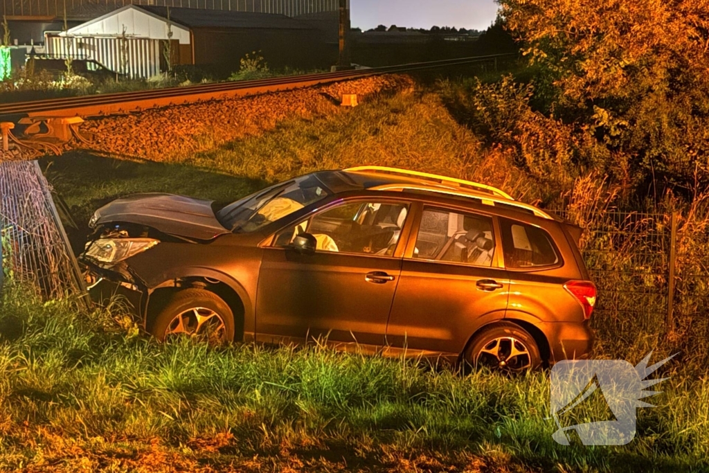 Auto vliegt uit de bocht en knalt tegen hek bij spoorwegovergang