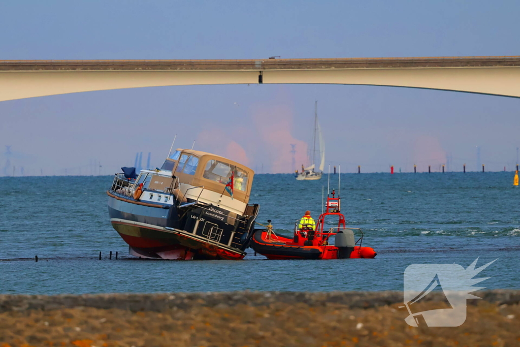 Boot loopt vast op dam, bergingsbedrijf schiet te hulp
