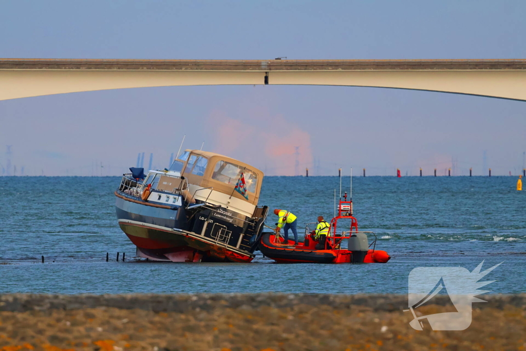 Boot loopt vast op dam, bergingsbedrijf schiet te hulp
