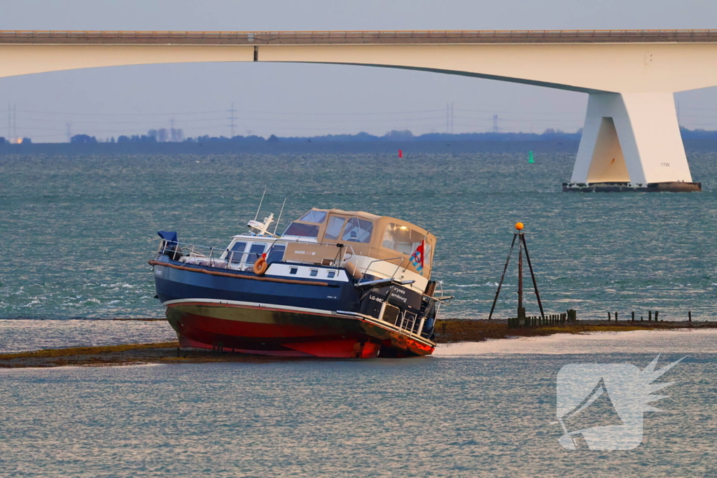 Boot loopt vast op dam, bergingsbedrijf schiet te hulp
