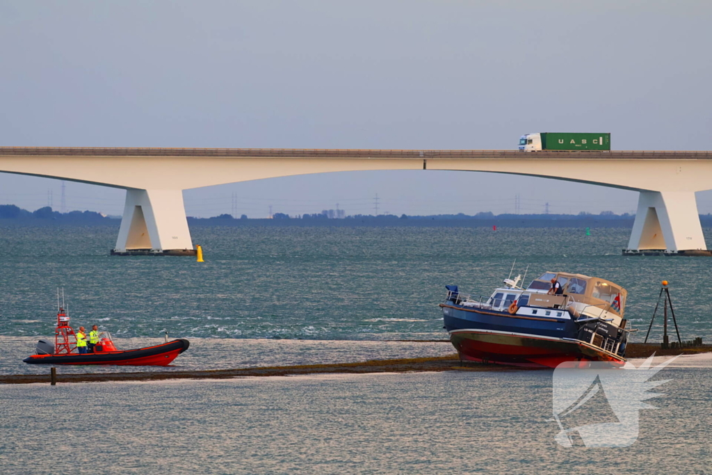 Boot loopt vast op dam, bergingsbedrijf schiet te hulp