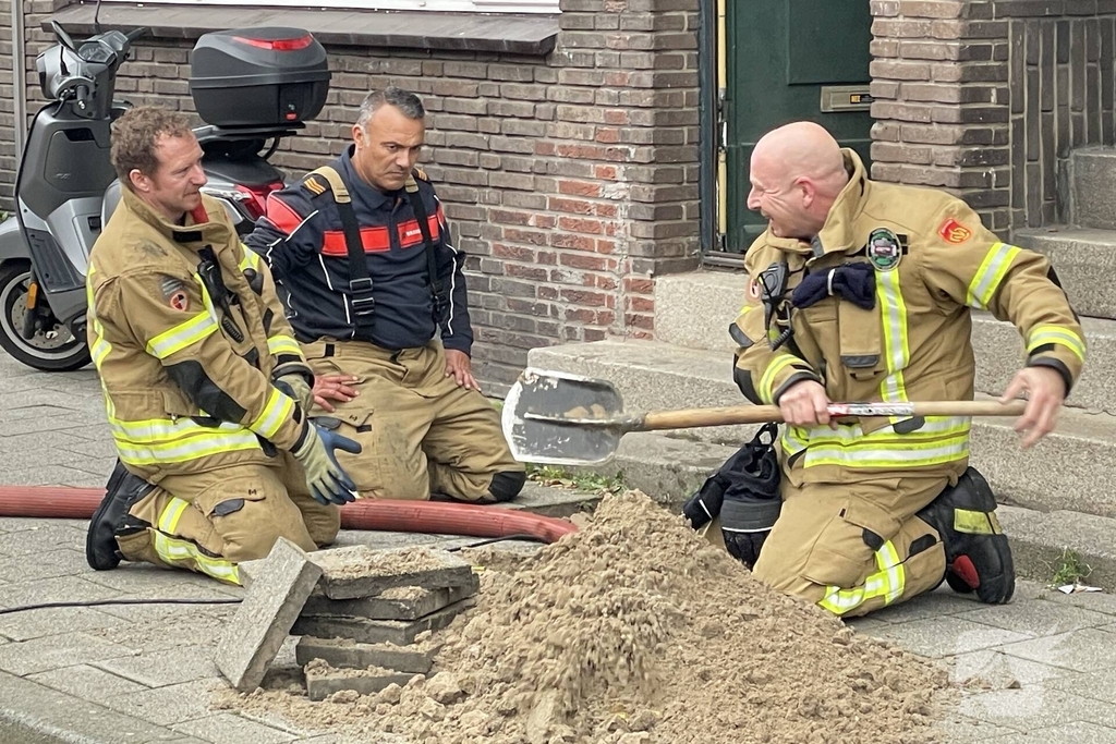 Brandweer graaft stoep open wegens leidingbreuk