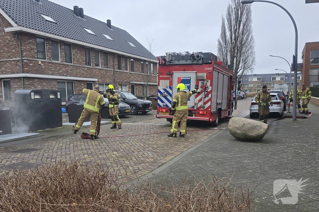 Container vat vlam door vuurwerk, omstanders doen bluspoging