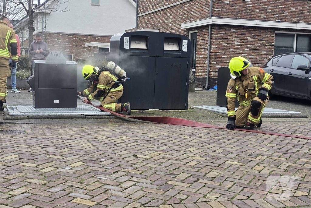 Container vat vlam door vuurwerk, omstanders doen bluspoging