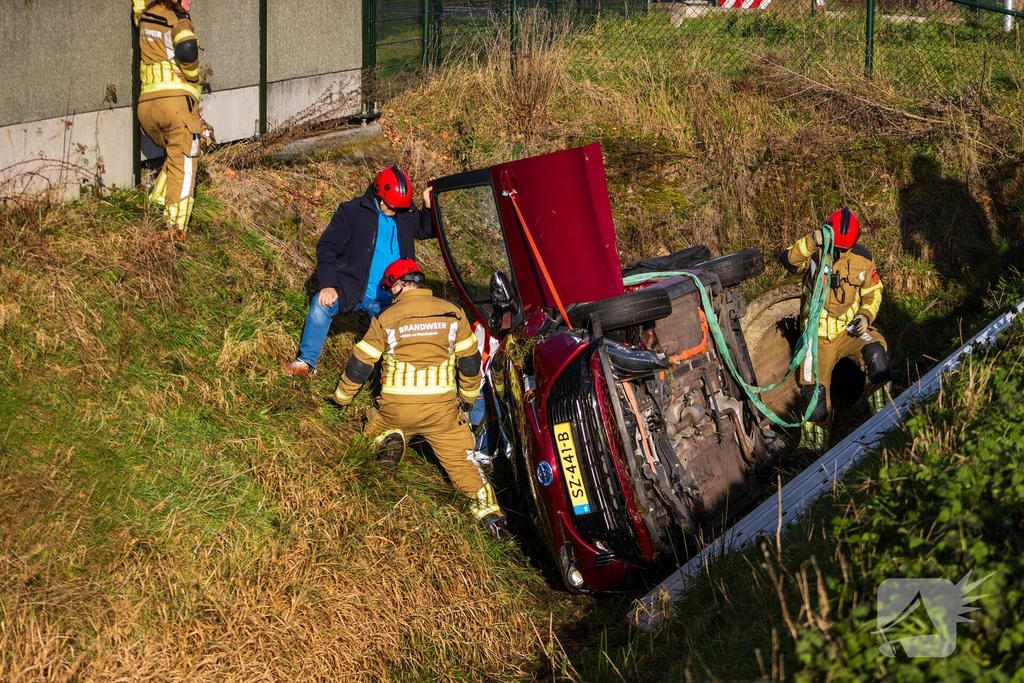 Auto op zijkant in greppel na ongeval