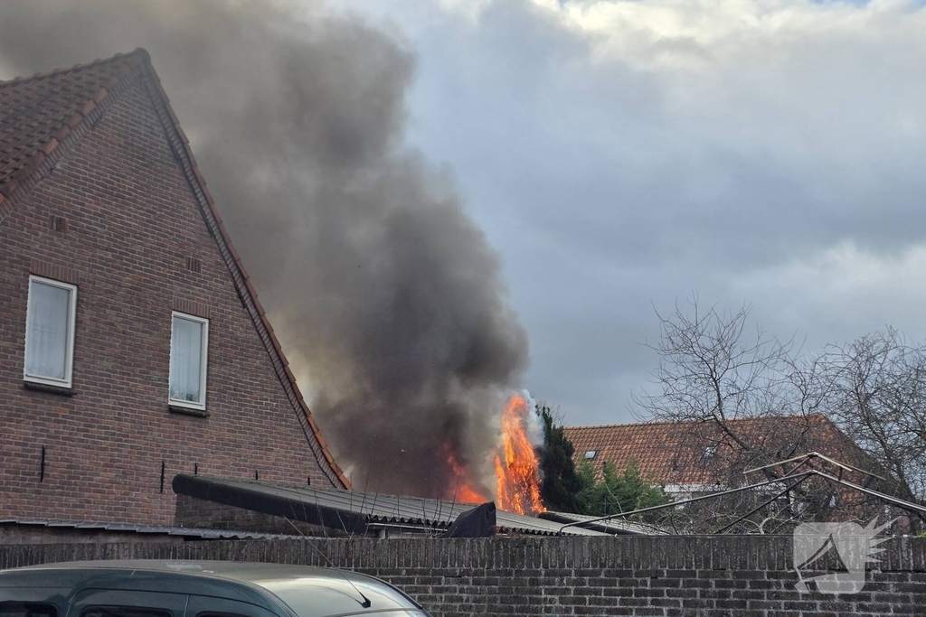 Vlammen, explosies en zwarte rook bij brand achter woning