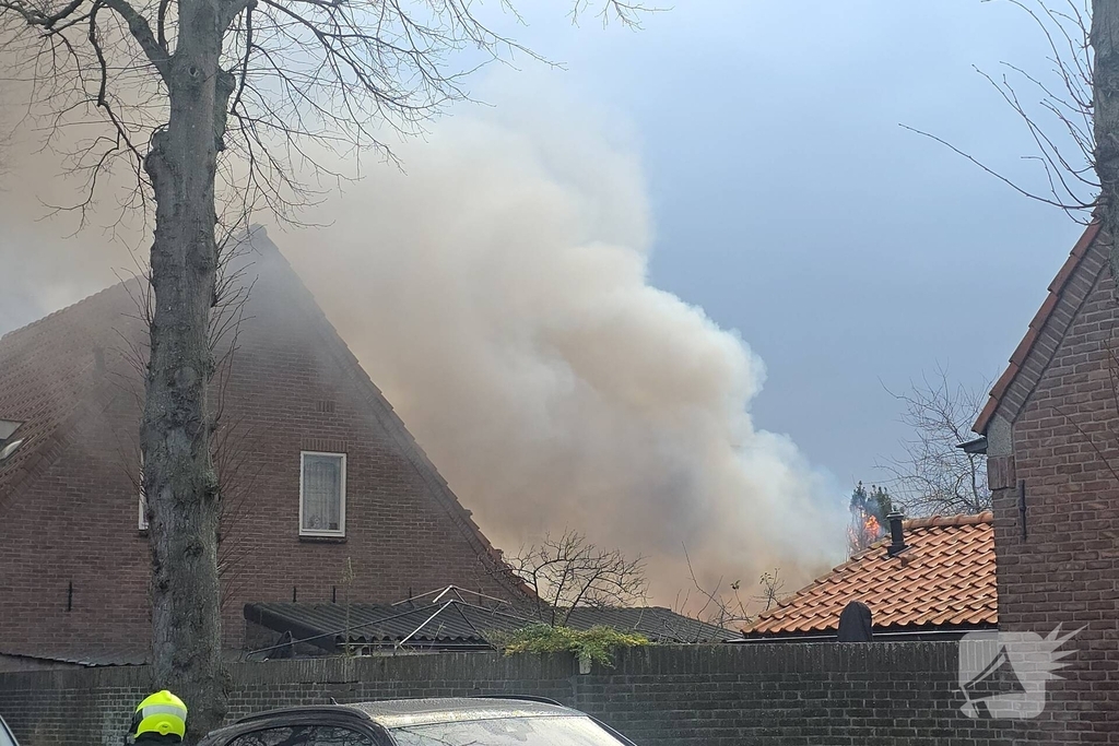 Vlammen, explosies en zwarte rook bij brand achter woning