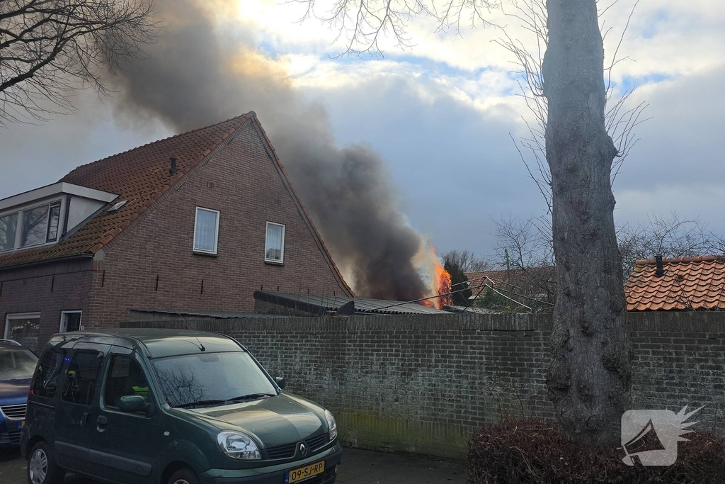 Vlammen, explosies en zwarte rook bij brand achter woning