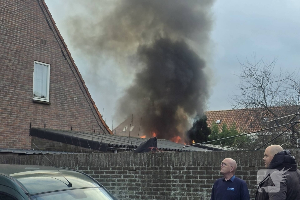 Vlammen, explosies en zwarte rook bij brand achter woning