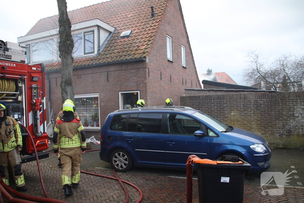Vlammen, explosies en zwarte rook bij brand achter woning