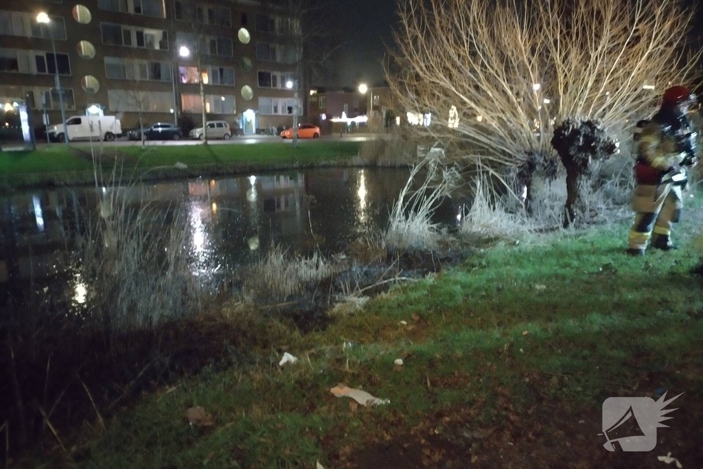 Brandweer blust brand langs sloot