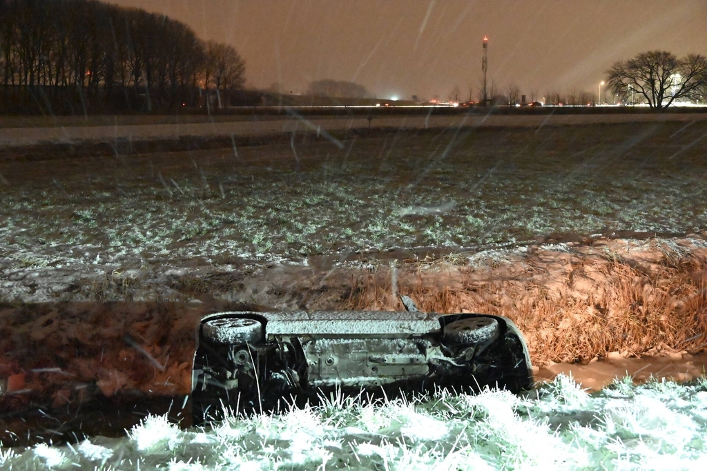 Auto belandt op zijkant in ondiepe sloot