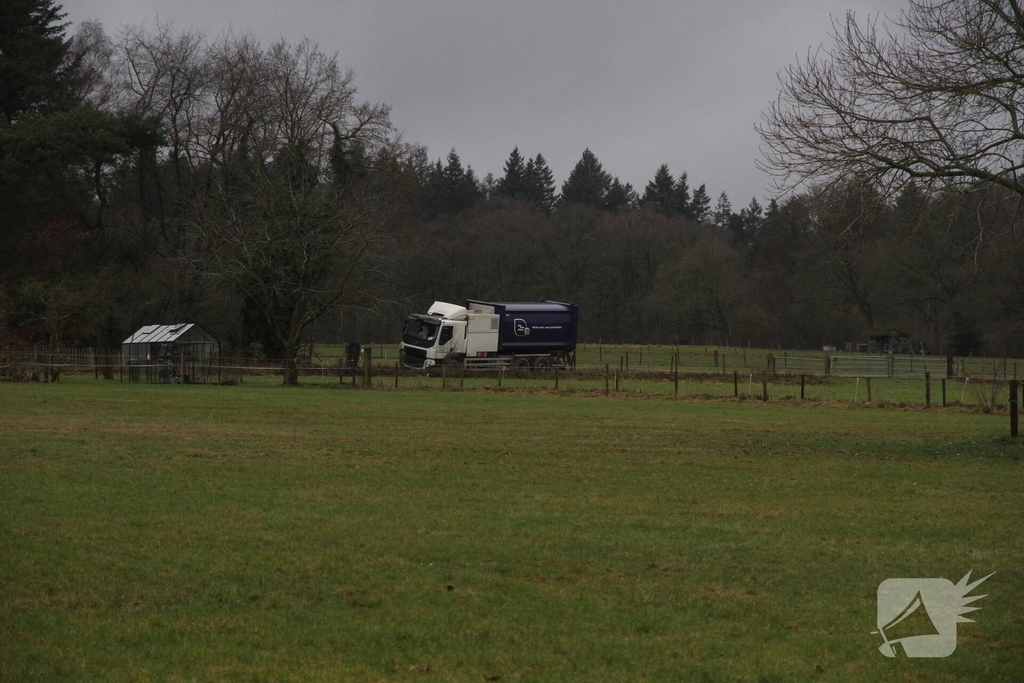 Vuilniswagen raakt paal en blijft vastzitten