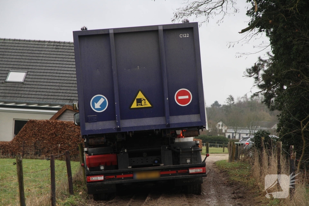 Vuilniswagen raakt paal en blijft vastzitten
