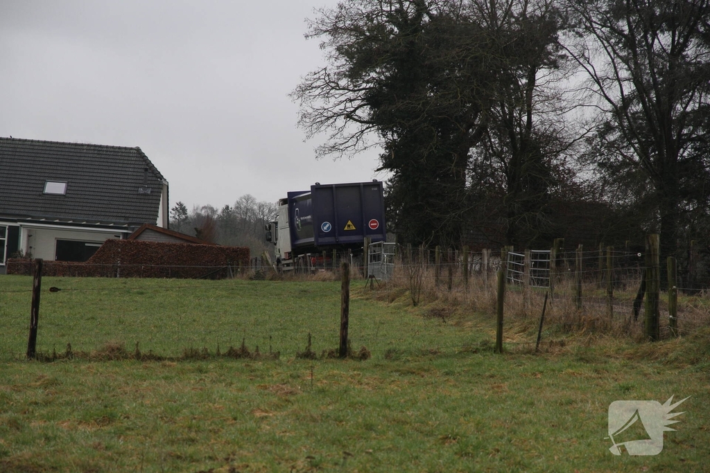 Vuilniswagen raakt paal en blijft vastzitten