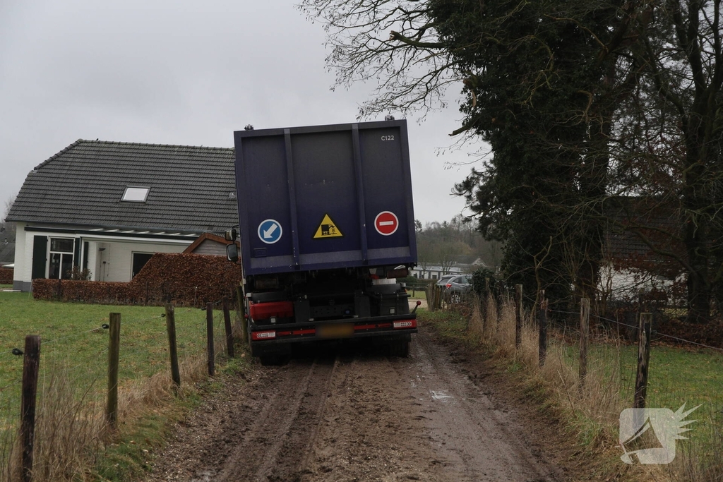 Vuilniswagen raakt paal en blijft vastzitten