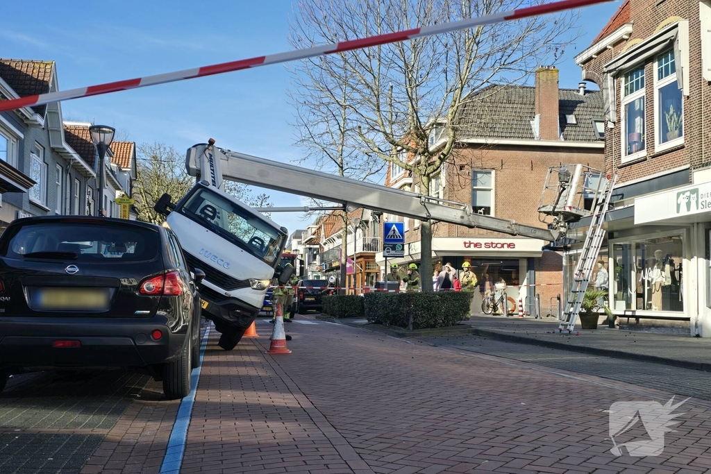 Hoogwerker kantelt tegen winkelpand
