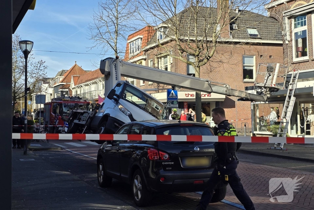 Hoogwerker kantelt tegen winkelpand