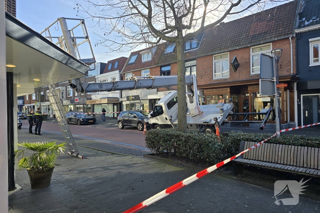 Hoogwerker kantelt tegen winkelpand