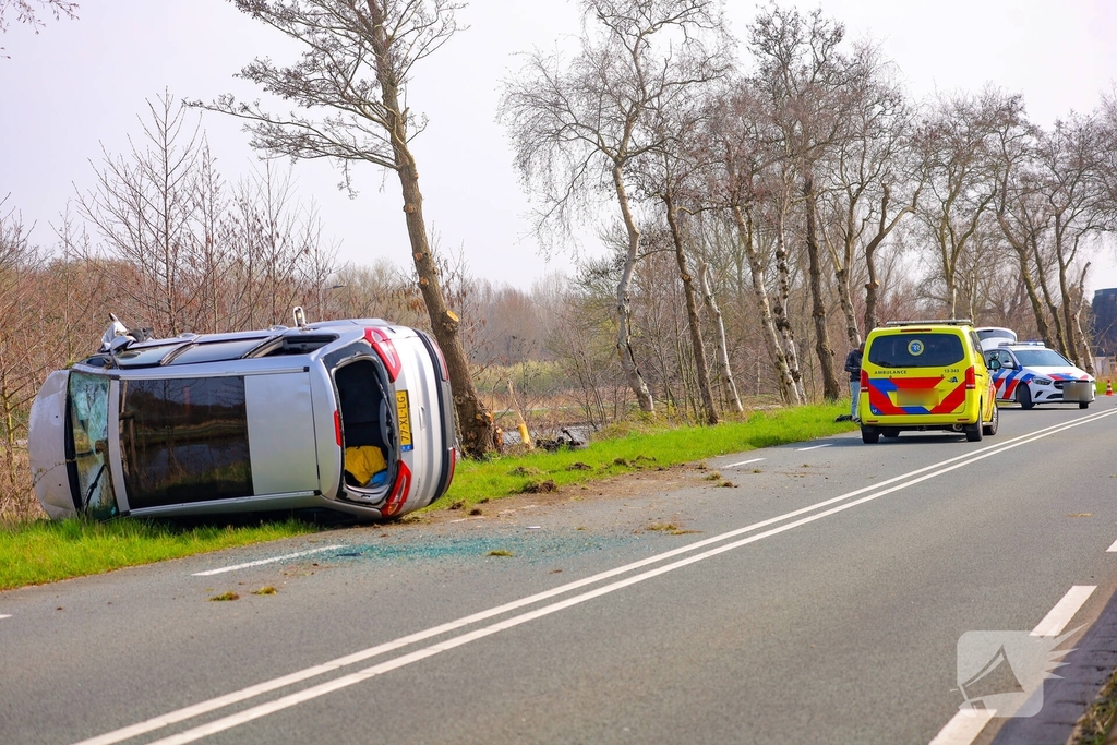 Auto belandt op zijn kant na botsing met boom