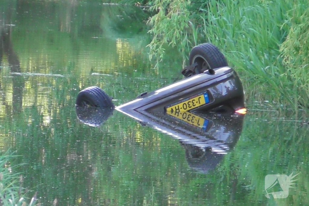 Auto belandt op de kop in het water, omstanders verrichten redding