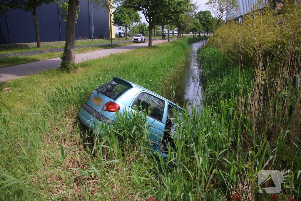 Omstanders halen inzittenden uit te water geraakt voertuig