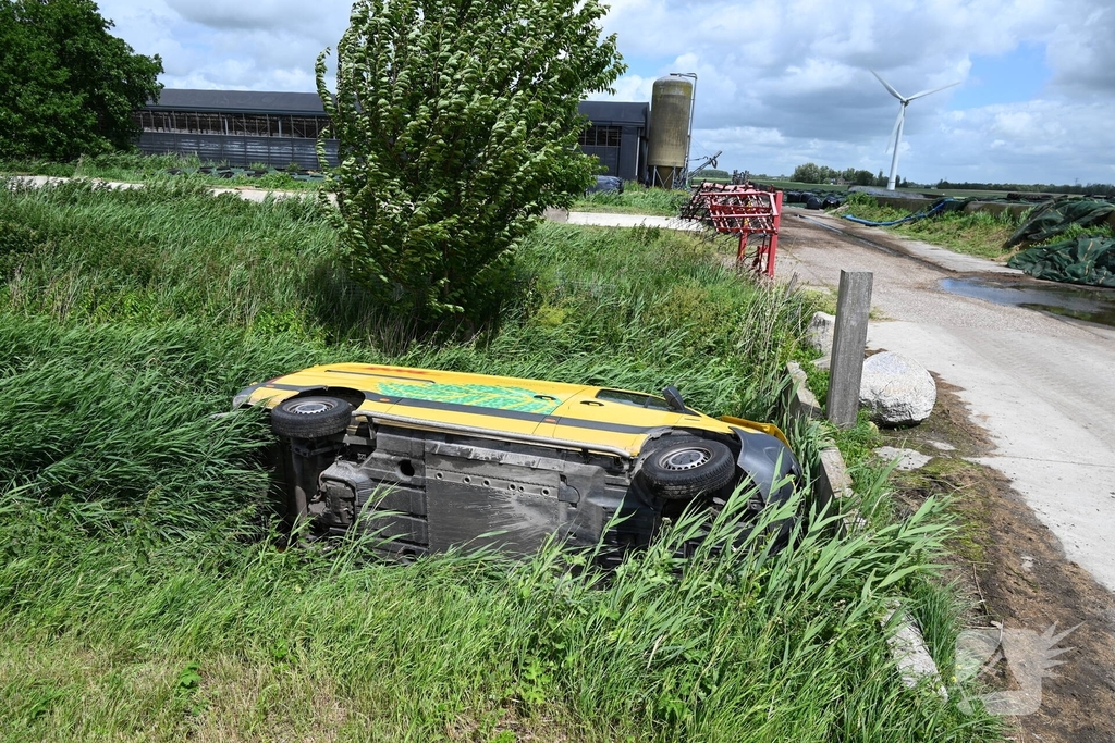 Bus van pakketdienst belandt op zijkant in sloot