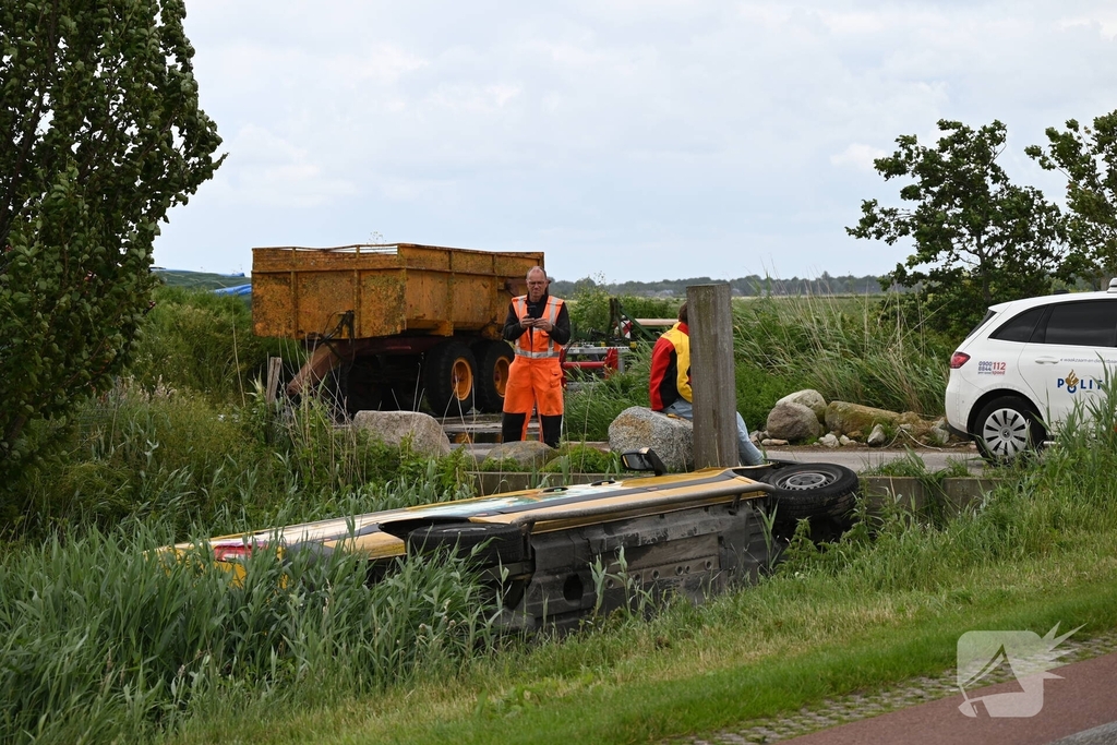 Bus van pakketdienst belandt op zijkant in sloot