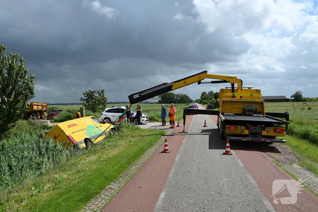 Bus van pakketdienst belandt op zijkant in sloot