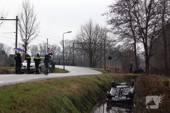 Auto vliegt uit bocht en komt ondersteboven in sloot