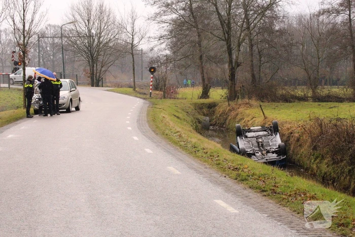 Auto vliegt uit bocht en komt ondersteboven in sloot