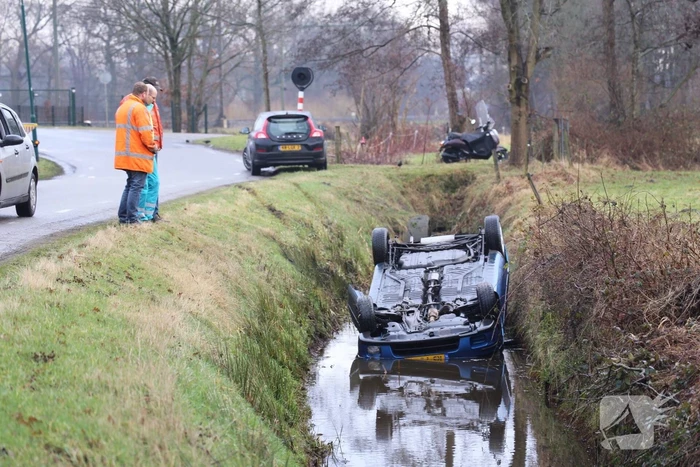 Auto vliegt uit bocht en komt ondersteboven in sloot