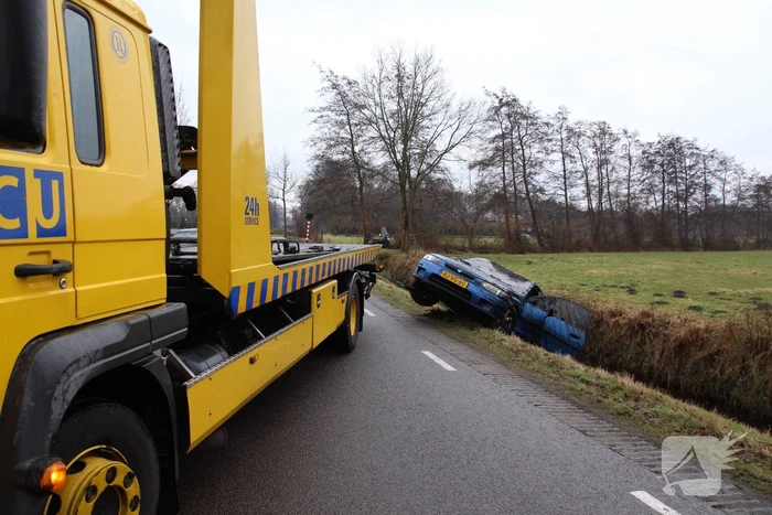 Auto vliegt uit bocht en komt ondersteboven in sloot