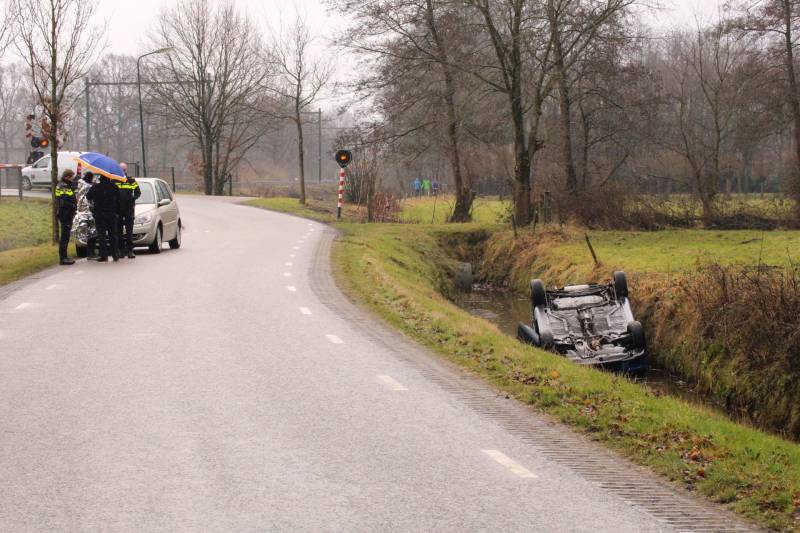 Auto vliegt uit bocht en komt ondersteboven in sloot