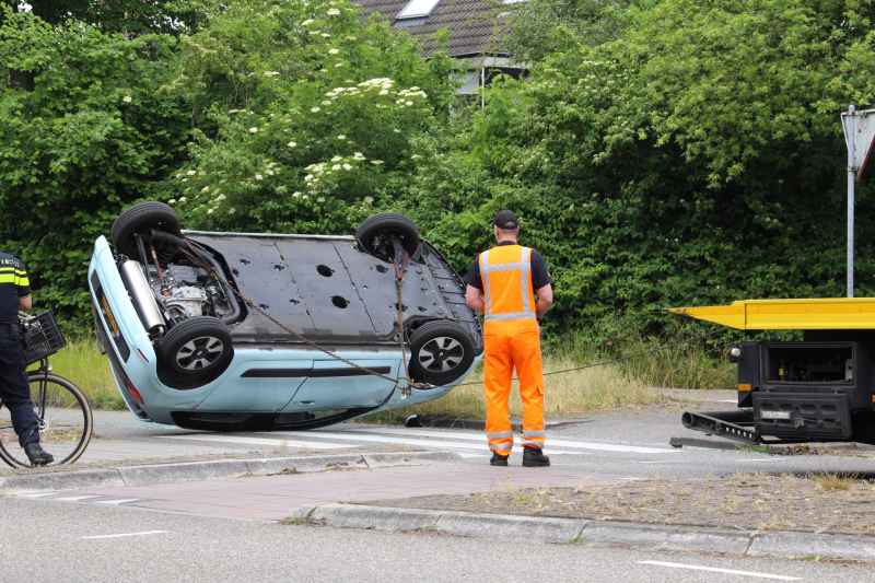 Auto over de kop na botsing