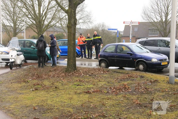 Auto en scooter botsen op rotonde