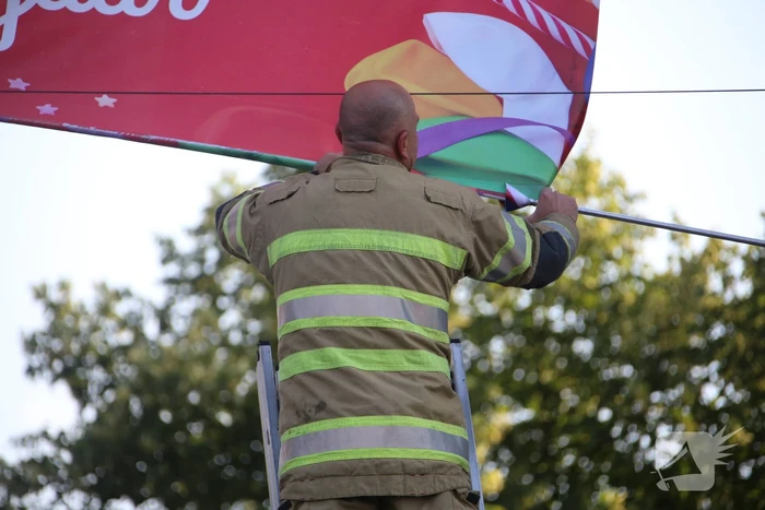 Brandweer zet loshangend reclamedoek vast