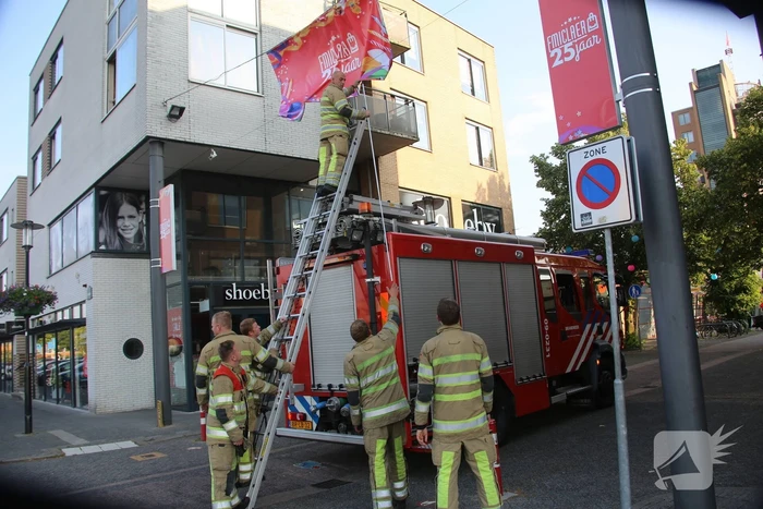 Brandweer zet loshangend reclamedoek vast