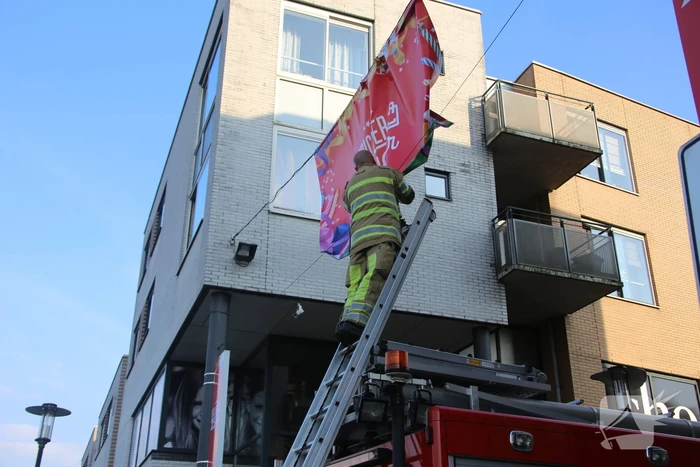 Brandweer zet loshangend reclamedoek vast