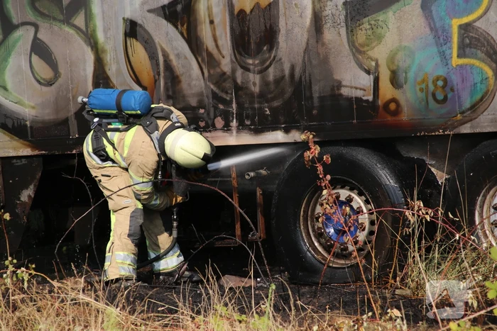 Brand nabij oude trailer in weiland