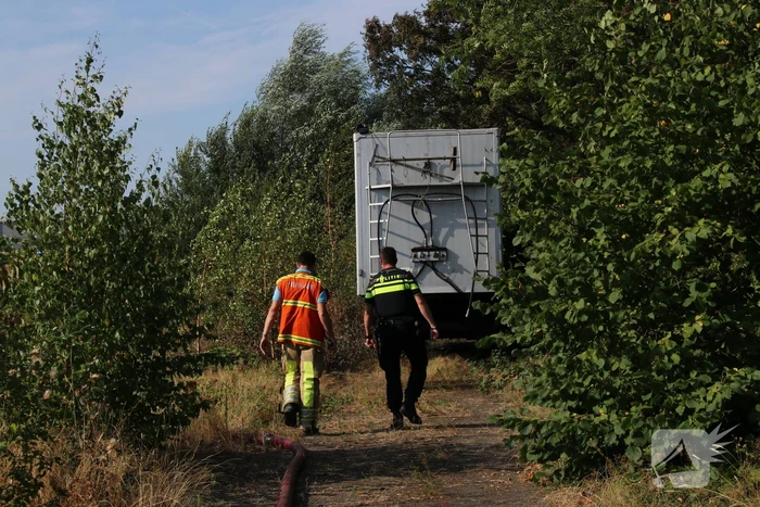 Brand nabij oude trailer in weiland