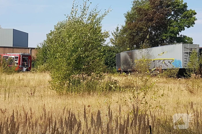 Brand nabij oude trailer in weiland